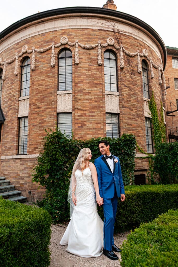 Bride and groom standing shoulder to shoulder looking at each other outside the Rainbow Room at Hotel Baker St. Charles IL.