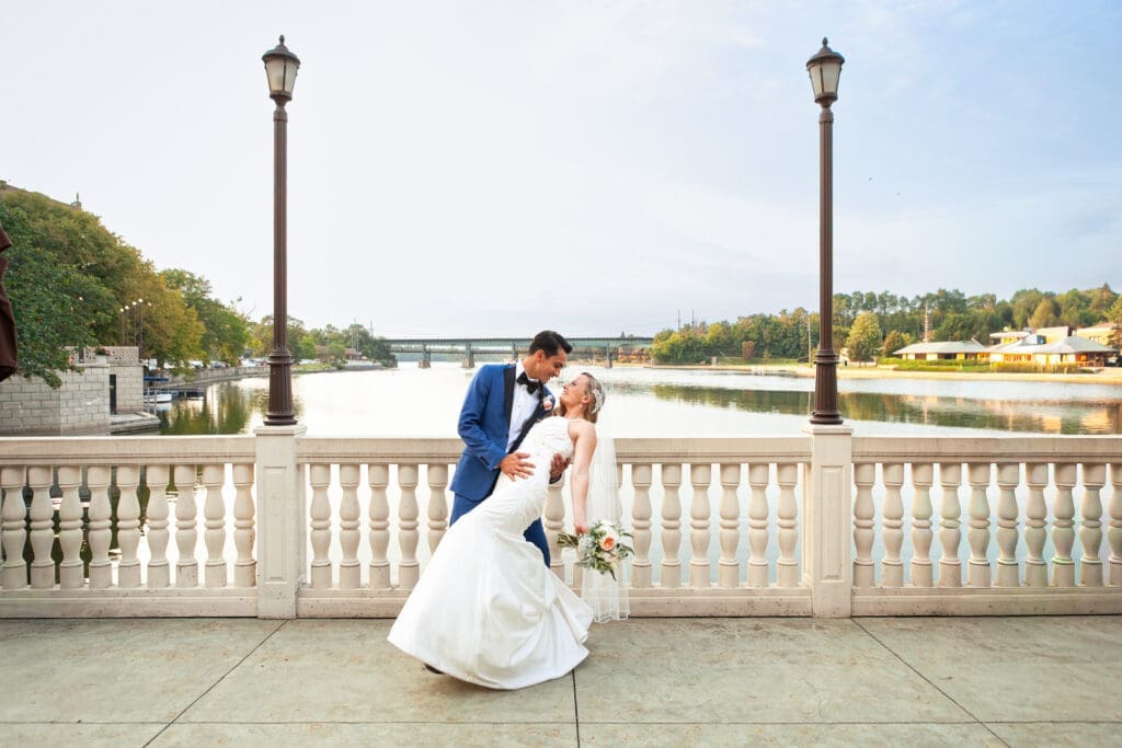 Groom dips bride by the Fox River in St. Charles at Hotel Baker.