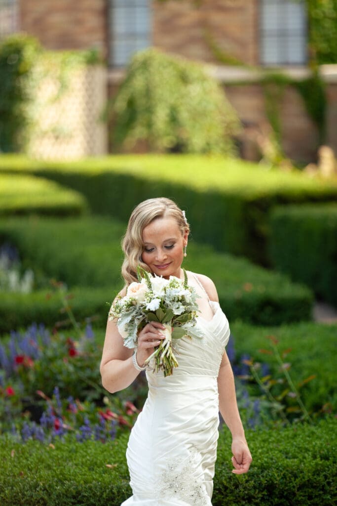 Bride smelling her flowers in the garden at Hotel Baker.