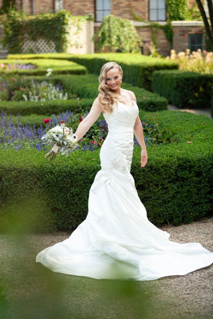 Beautiful bride posing with her flowers in the English style garden at Hotel Baker Saint Charles IL.