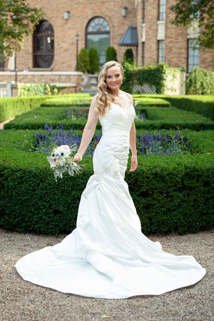 Smiling blonde bride with flowers in the courtyard at Hotel Baker Saint Charles IL.