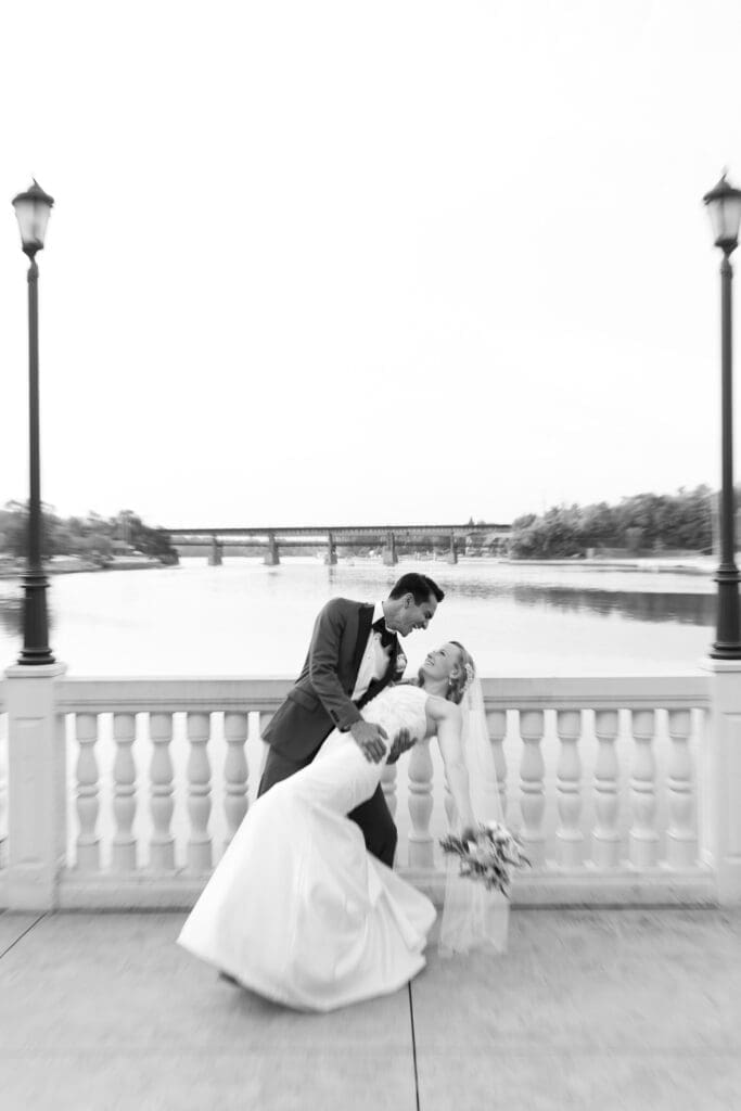 Groom dipping bride by the Fox River at Hotel Baker in black and white.