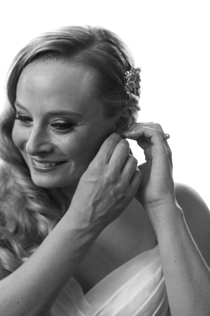 Smiling bride putting her earrings on at Hotel Baker St. Charles, IL