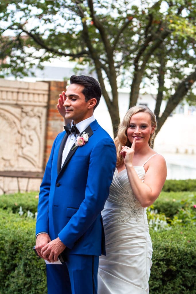 Beautiful bride puts her hands over the groom's eyes before their first look at Hotel Baker.
