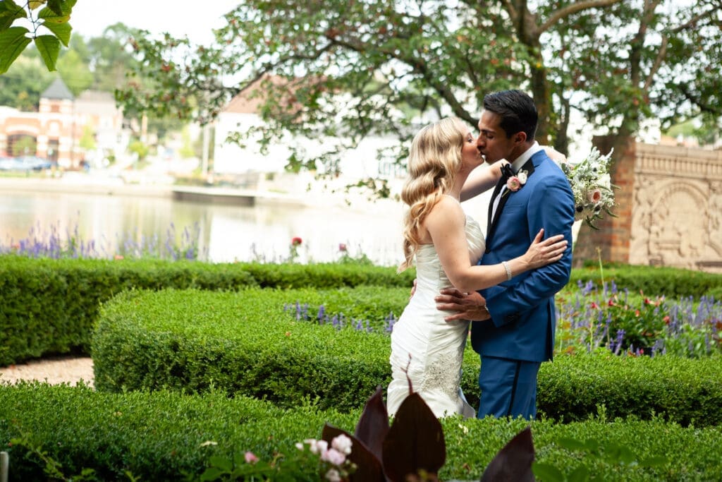 Bride and groom kissing in the English-styled private garden at Hotel Baker.