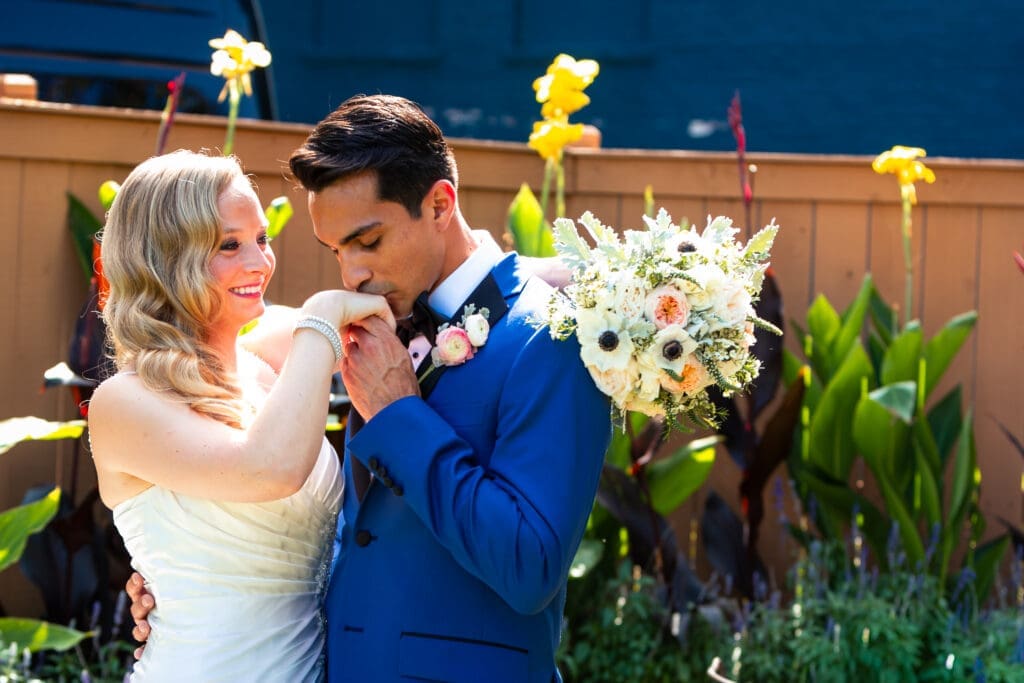 Groom kissing bride's hand at Hotel Baker.