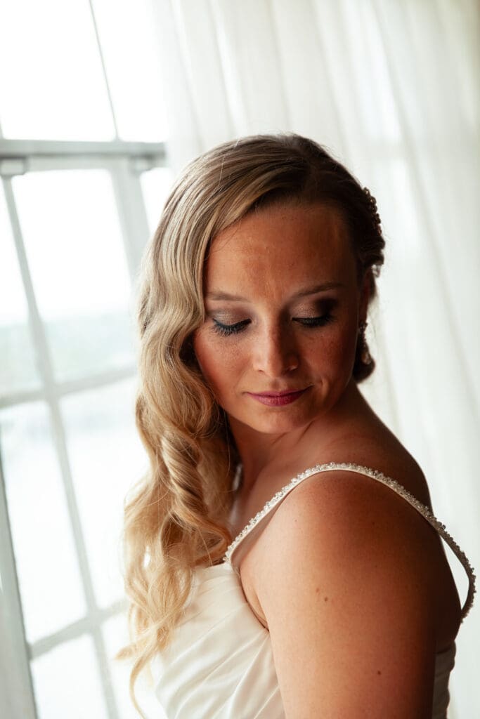 Beautiful bride posing in front of window in her wedding dress at Hotel Baker.