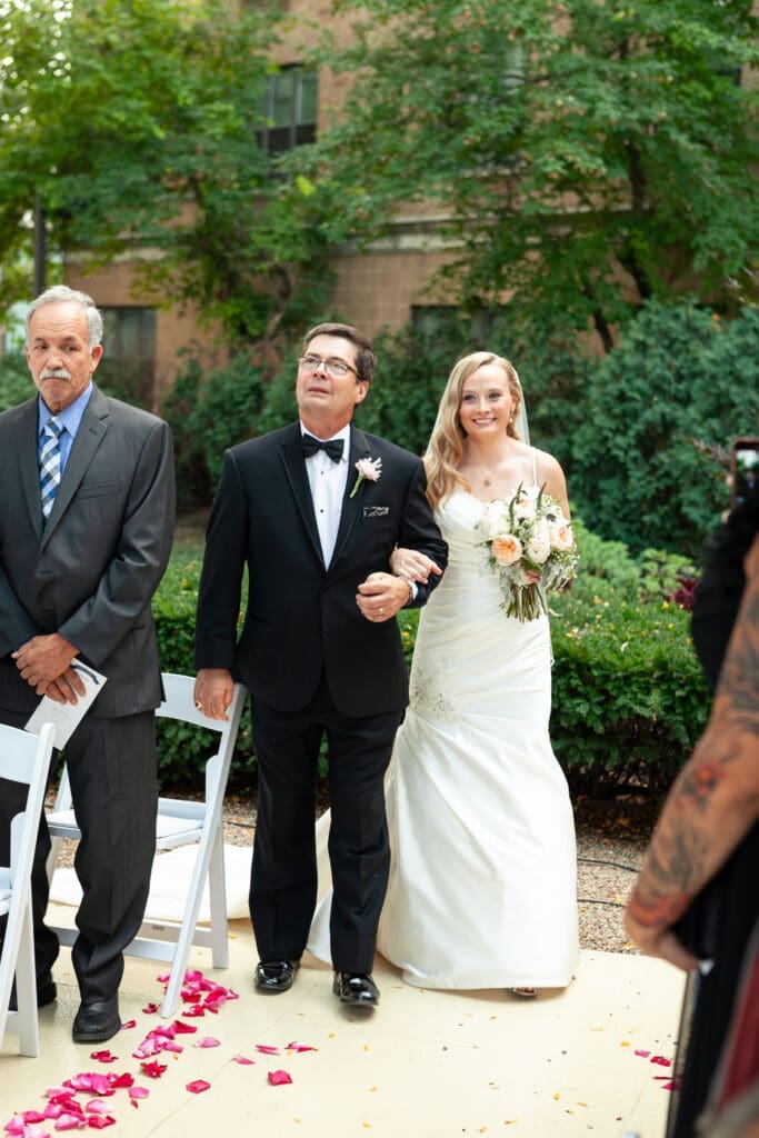 Beautiful smiling bride being walked down the aisle by her father.