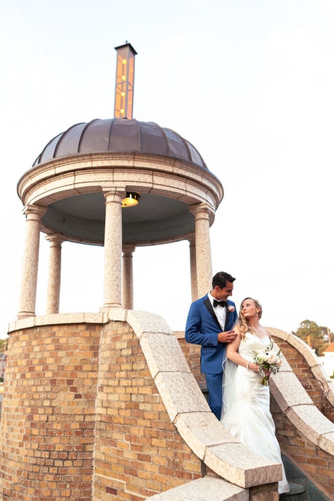 Brides back to the grooms chest as they look at each other near the gazebo at Hotel Baker.