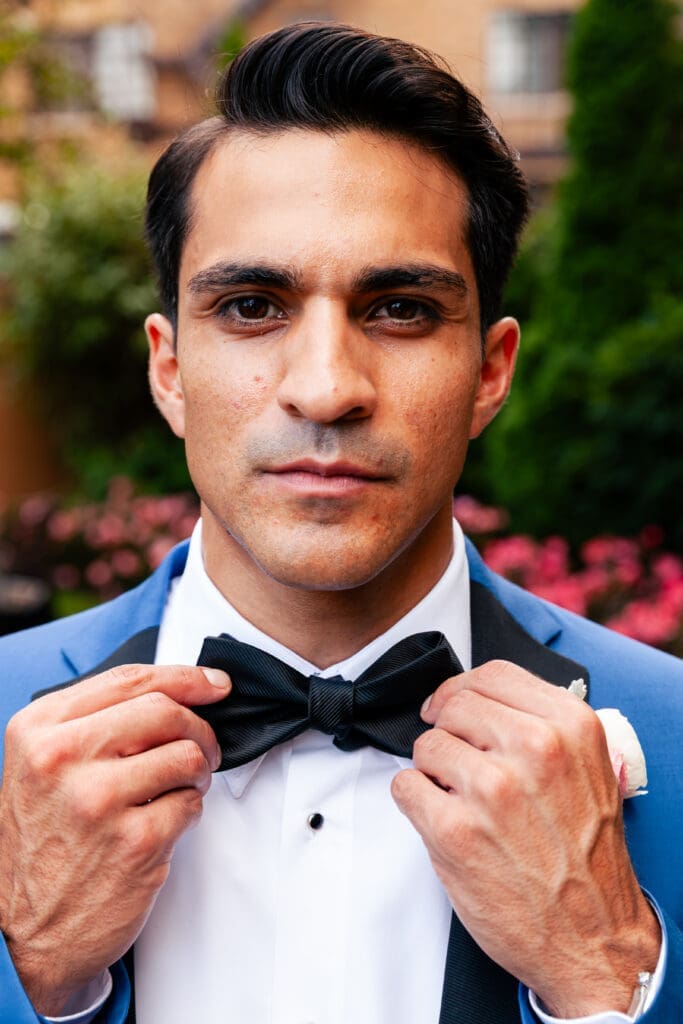 Handsome Groom at Hotel Baker Saint Charles IL fixing his bow tie looking into the camera.