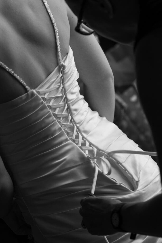 Bridesmaid lacing up brides dress add Hotel Baker Saint Charles IL.
