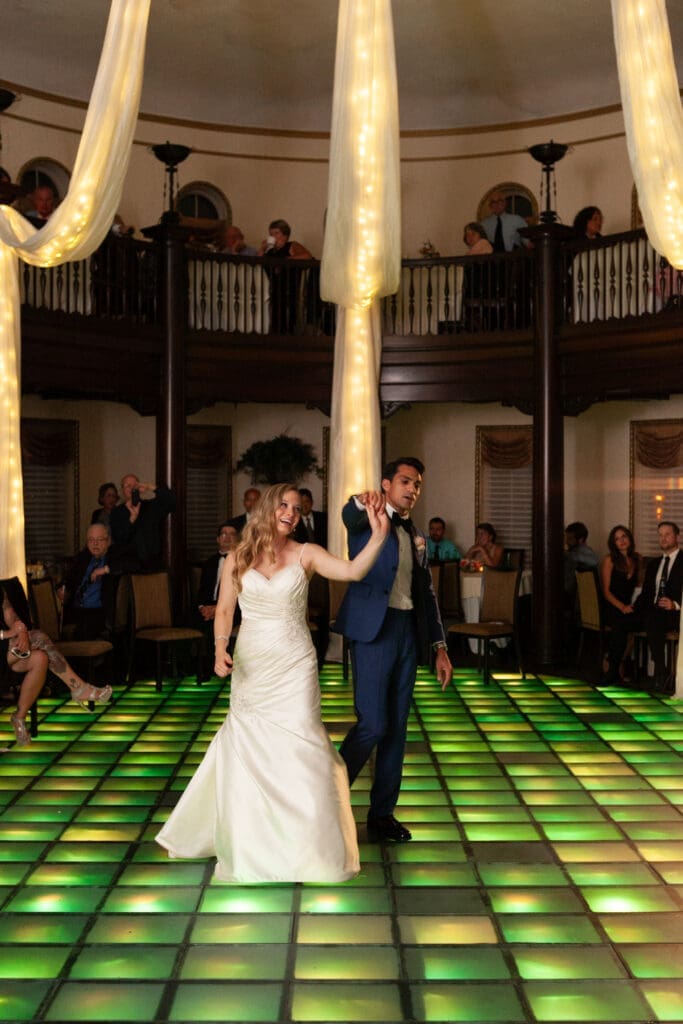 Bride and groom share first dance in the Rainbow Room at Hotel Baker with a light-up dancefloor.