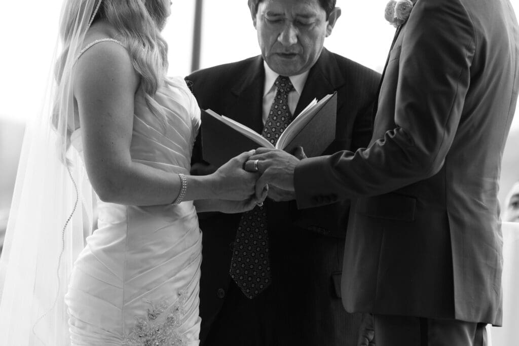 Bride and groom holding hands at the altar exchanging rings together on their wedding day.