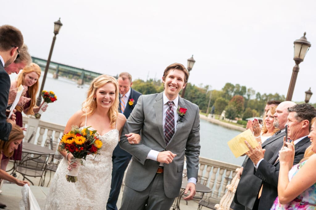 Bride and groom just married walking back down the aisle ending their ceremony smiling among their cheering guests.