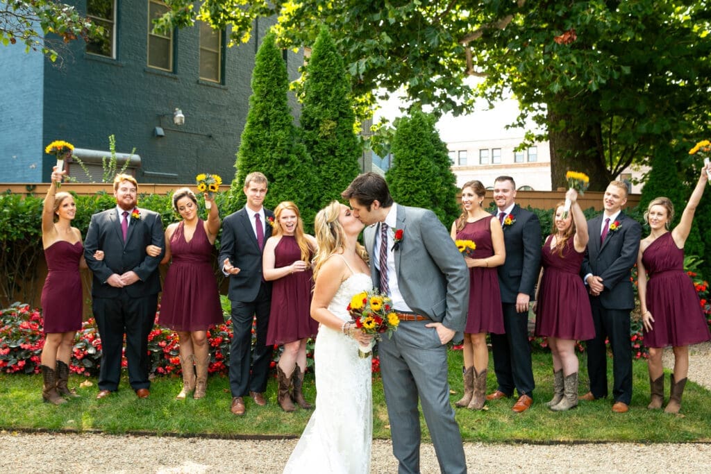 Bride and groom kissing in front of bridal party.