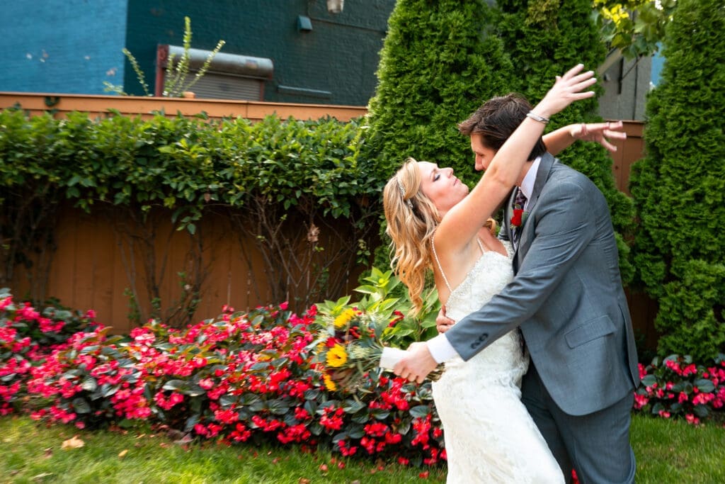 Action shot of the bride throwing her arms around her groom in the garden at Hotel Baker.