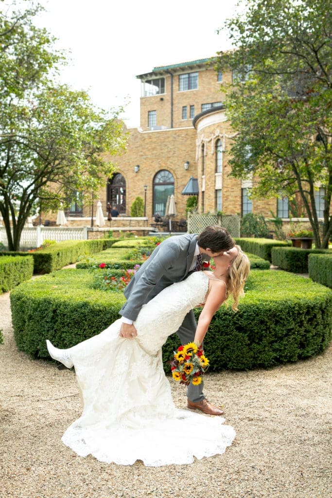 Groom dipping bride and kissing her in the private English garden at Hotel Baker.