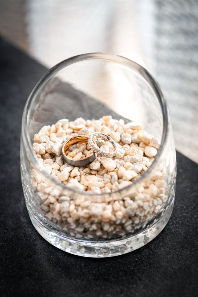 Luxury wedding rings sitting in a vase laying on top of each other.
