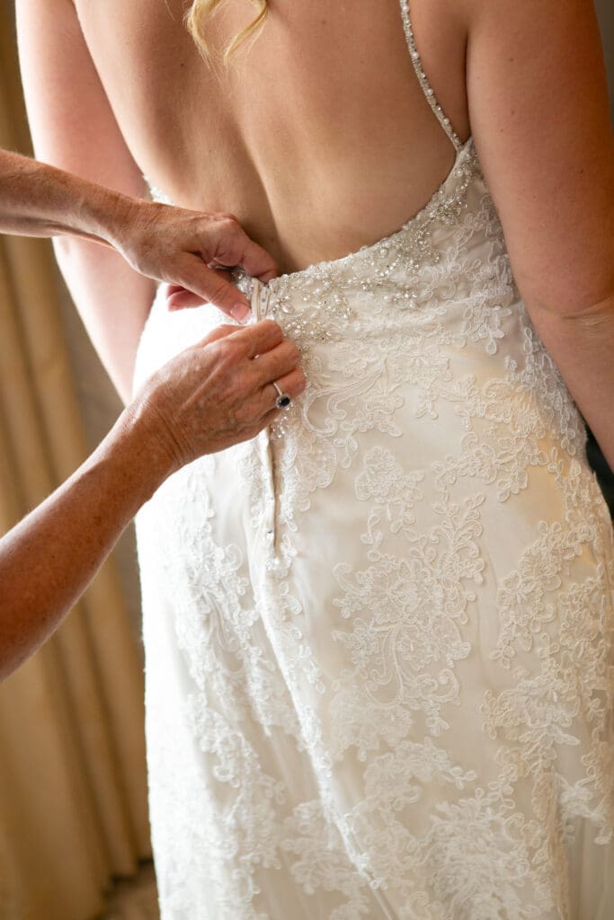 Mother of the bride zips up the bride's dress at Hotel Baker in the bridal suite.
