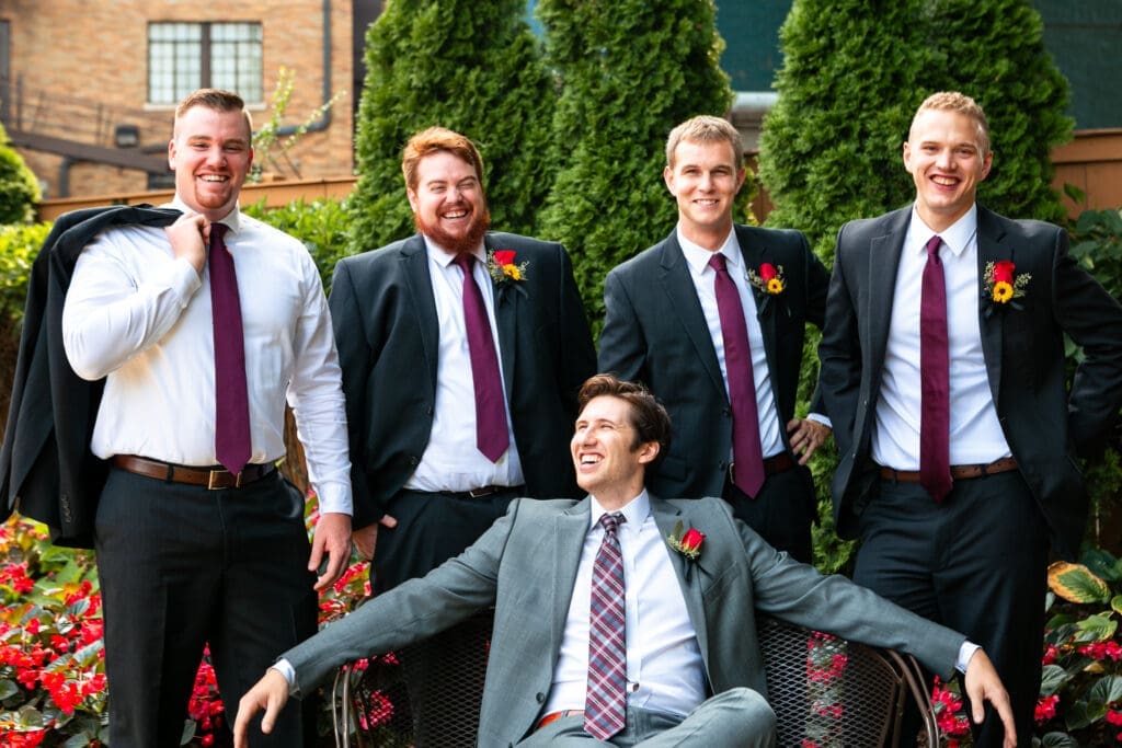Groom sitting and laughing with groomsmen around him at Hotel Baker.