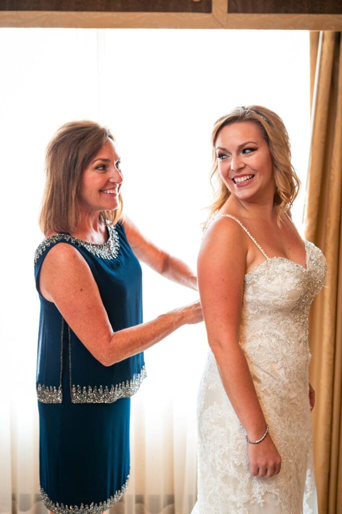 Bride looking back at her mother while she fixes her dress at Hotel Baker.