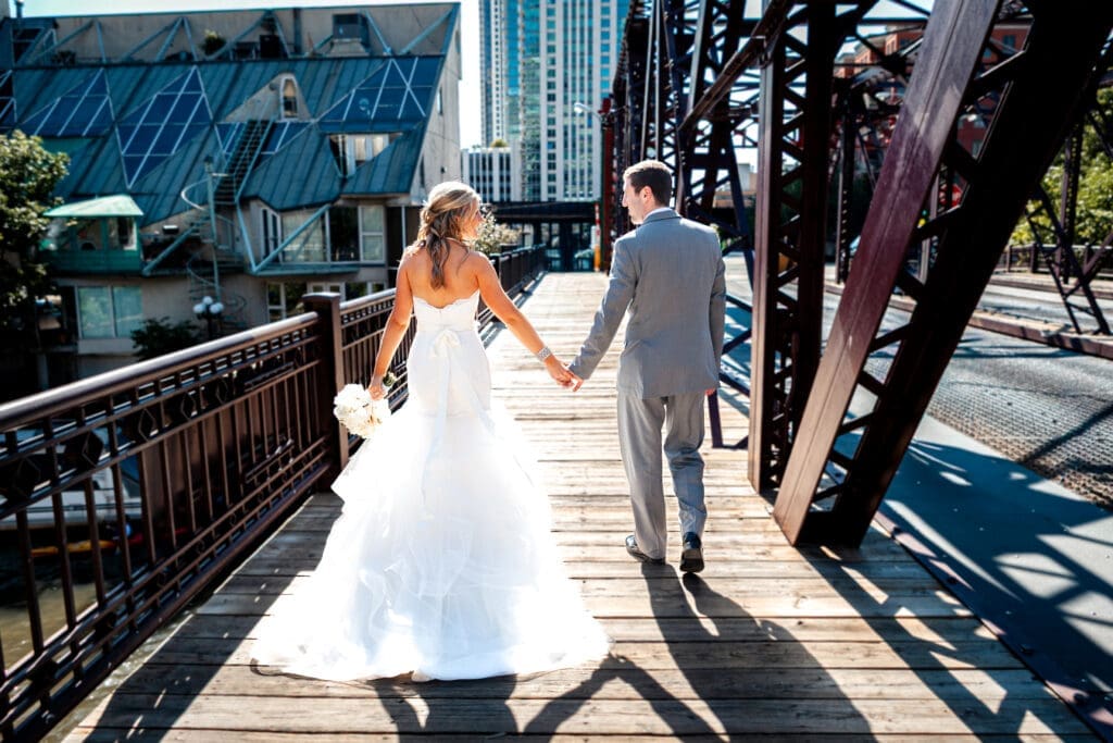 Bride and groom walking away in the sunlight on a bridge in Chicago.