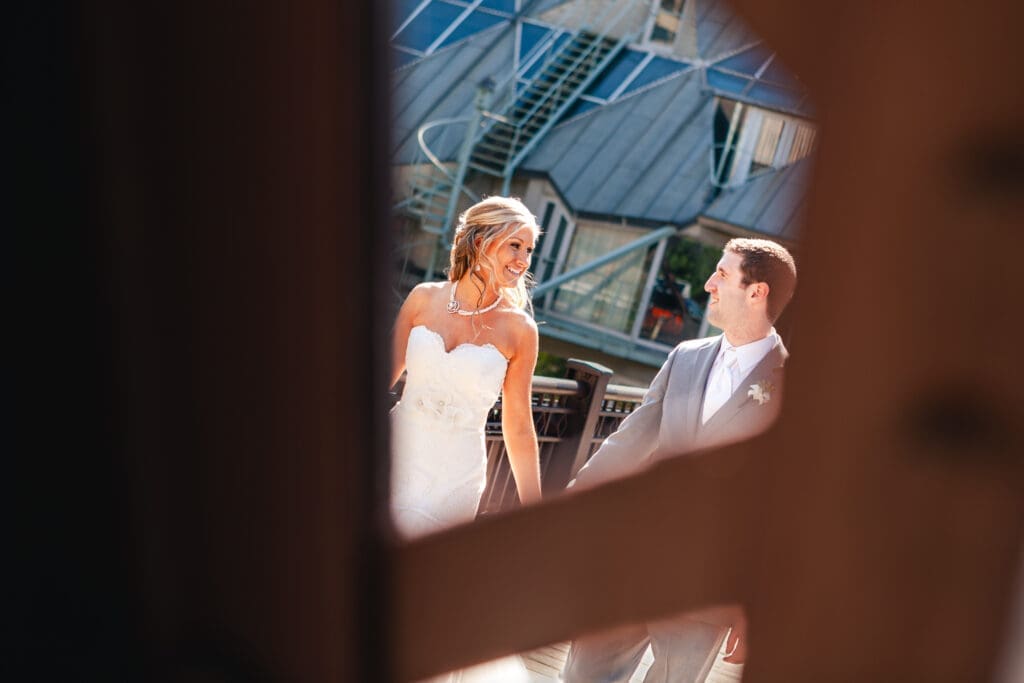 Bride and groom walking on a bridge in an artistic shot through the bridge's structure.