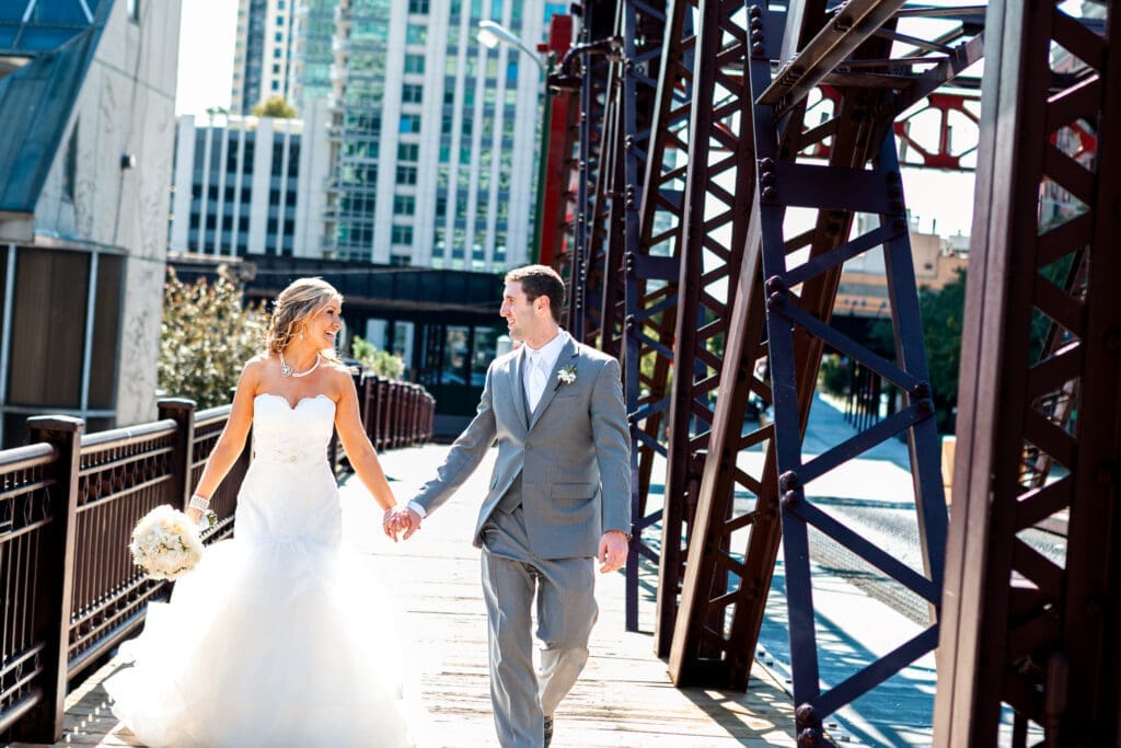 Bride and groom walking hand in hand on their wedding day on a bridge in Chicago.