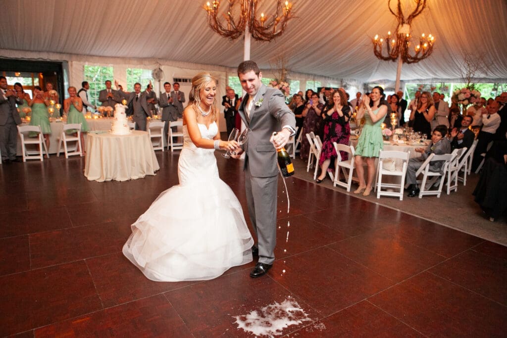 Bride laughing as the groom holds a bottle erupting full of champaign onto the dancefloor at a private estate wedding reception in Chicago.