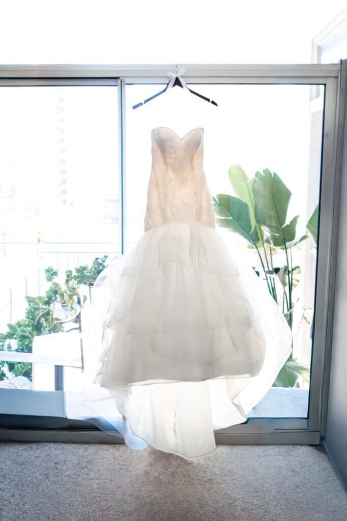 Custom luxury wedding dress hanging in front of a window in the bridal suite and the Langham Chicago