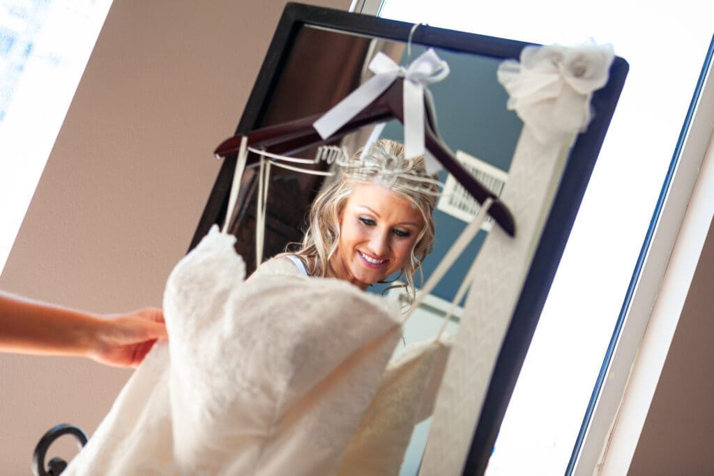 Bride checking out her wedding dress hanging on a mirror in the bridal suite and the Langham Chicago.