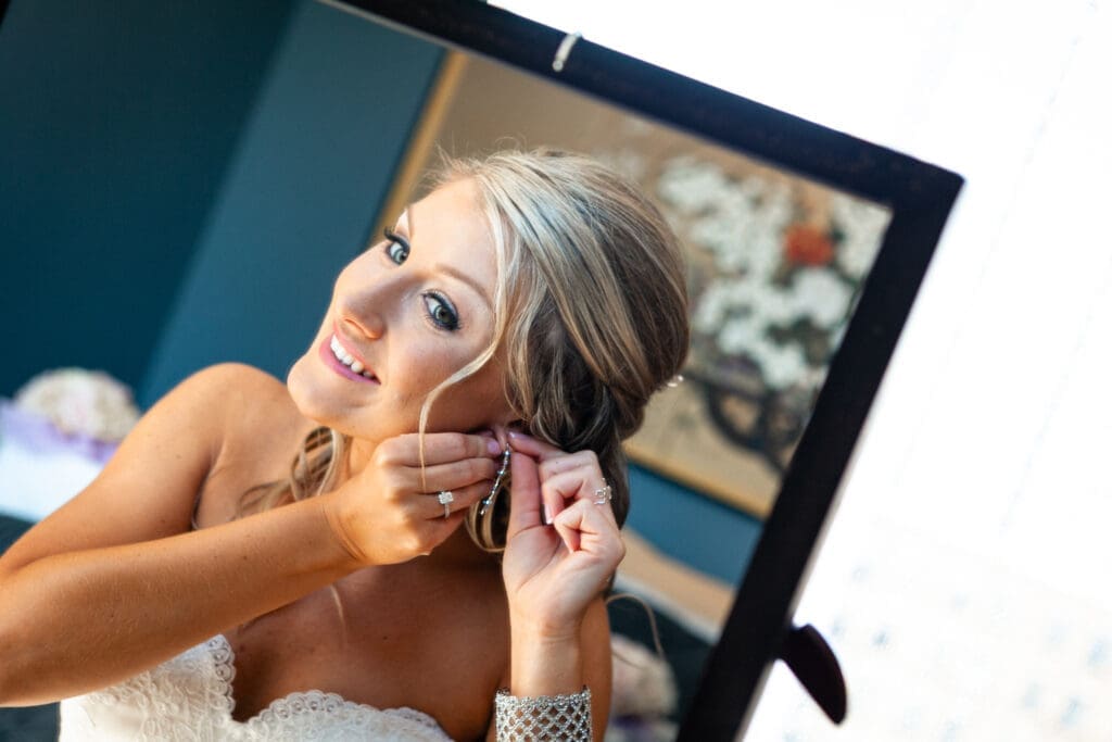 Bride looking at herself in the mirror while putting on her wedding earrings at the Langham Chicago.