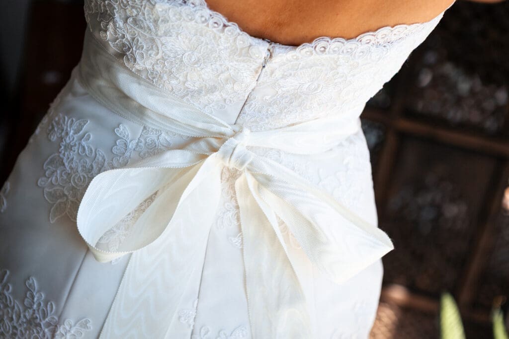 Details of the brides dress withe a large ribbon bow tied in the back.