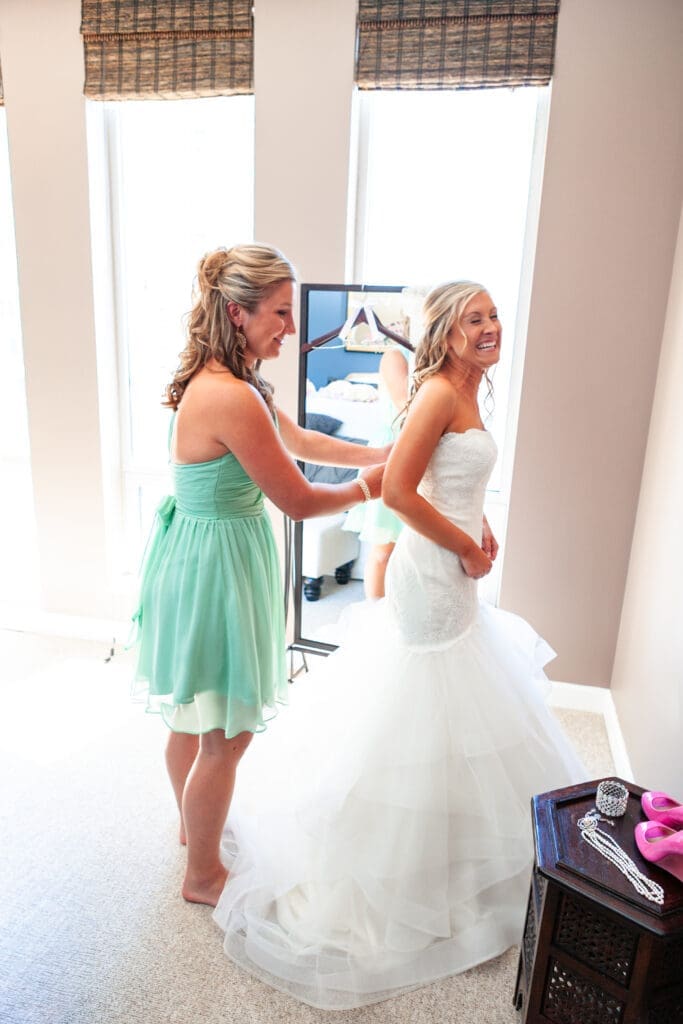 Bride laughing as her bridesmaid fixes her dress at the Langham Chicago.
