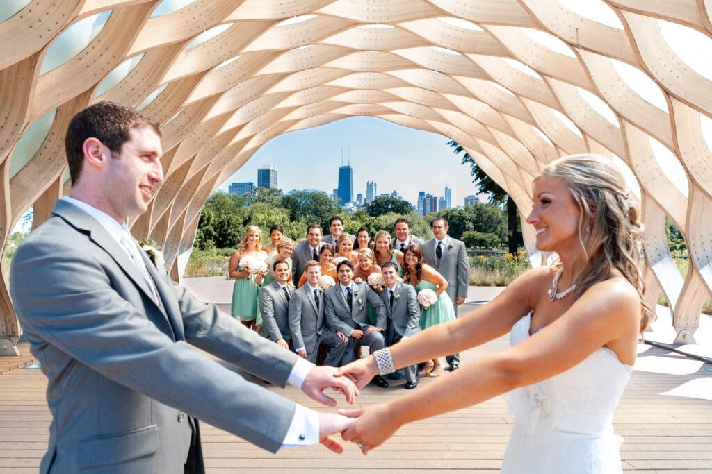Bride and groom holding hands in the foreground with their bridal party behind them at Lincoln Park Zoo with the Chicago skyline behind them.