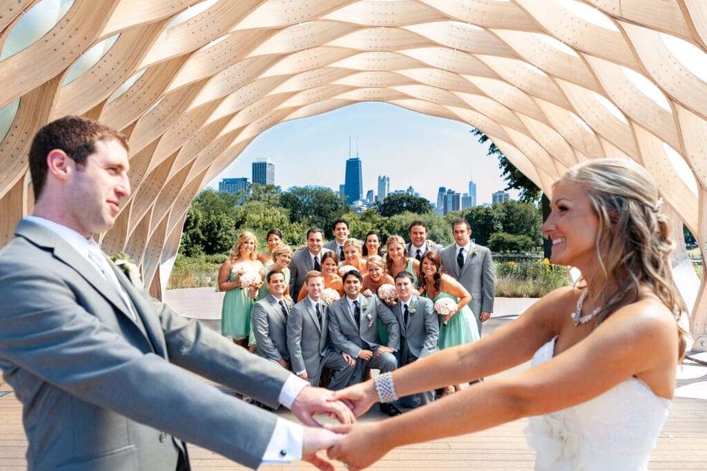 Bride and groom holding hands in the foreground with their bridal party behind them at Lincoln Park Zoo with the Chicago skyline behind them.