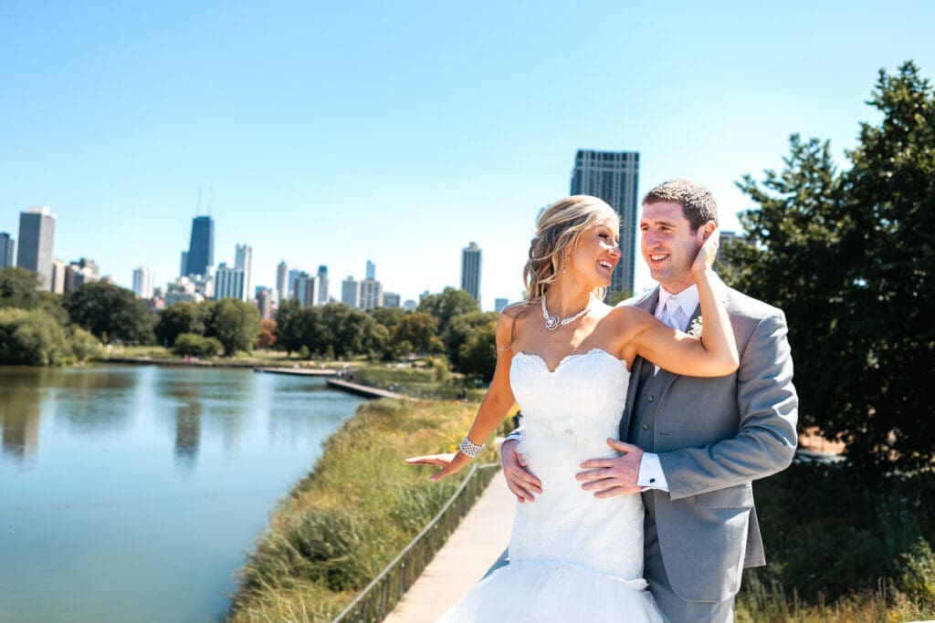 Bride with her arm up around the groom's head with the Chicago skyline behind them.