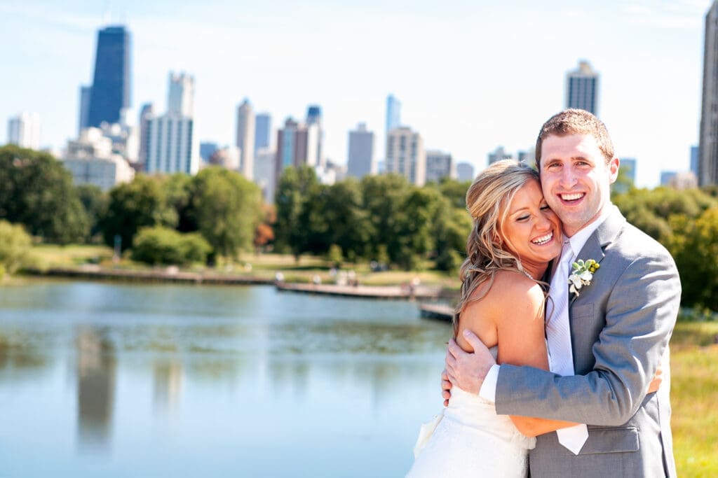 Groom holding laughing bride on front of Chicago skyline.
