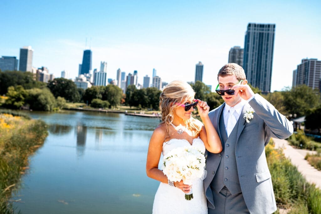 Bride and groom holding their sunglasses looking at each other in front the Chicago city skyline.